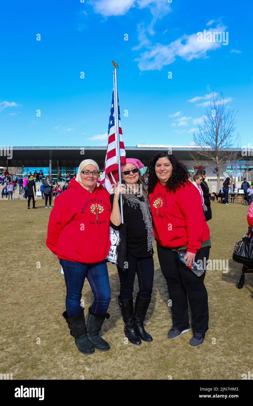 Two women with Muslims 4 Mercy Sweatshirts standing with woman in pussy hat with American Flag at Womens March in Tulsa Oklahoma USA 1-20-2018 Stock Photo