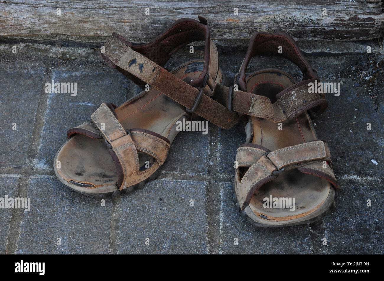Well-worn pair of adult men's sandals left on back doorstep Stock Photo