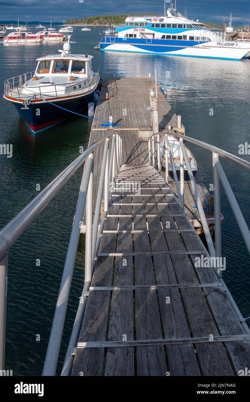 Wooden ramp with iron rails lead down to a dock off Bar Harbor Maine, with tourist, pleasure and lobster boats in Frenchman bay. USA. Stock Photo