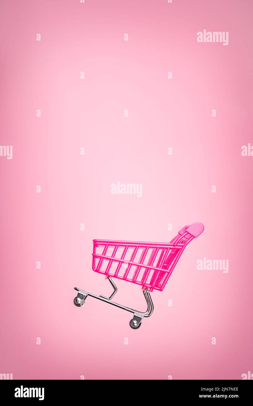 Empty trolley cart isolated pink background. Pink shopping trolley supermarket concept. Toy pink concept sales online shopping cart supermarket sales Stock Photo