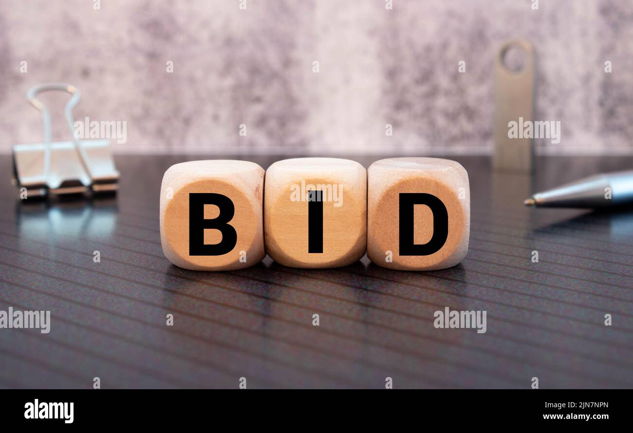 three wooden cubes with letters BID, on white table and diagram, business concept Stock Photo