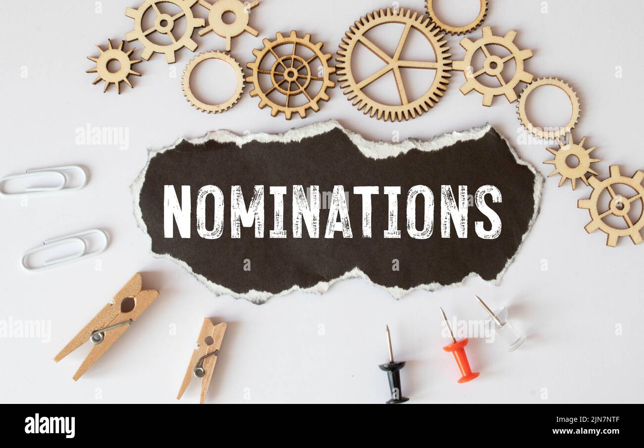 The word NOMINATIONS written on a black piece of paper and a wooden table Stock Photo