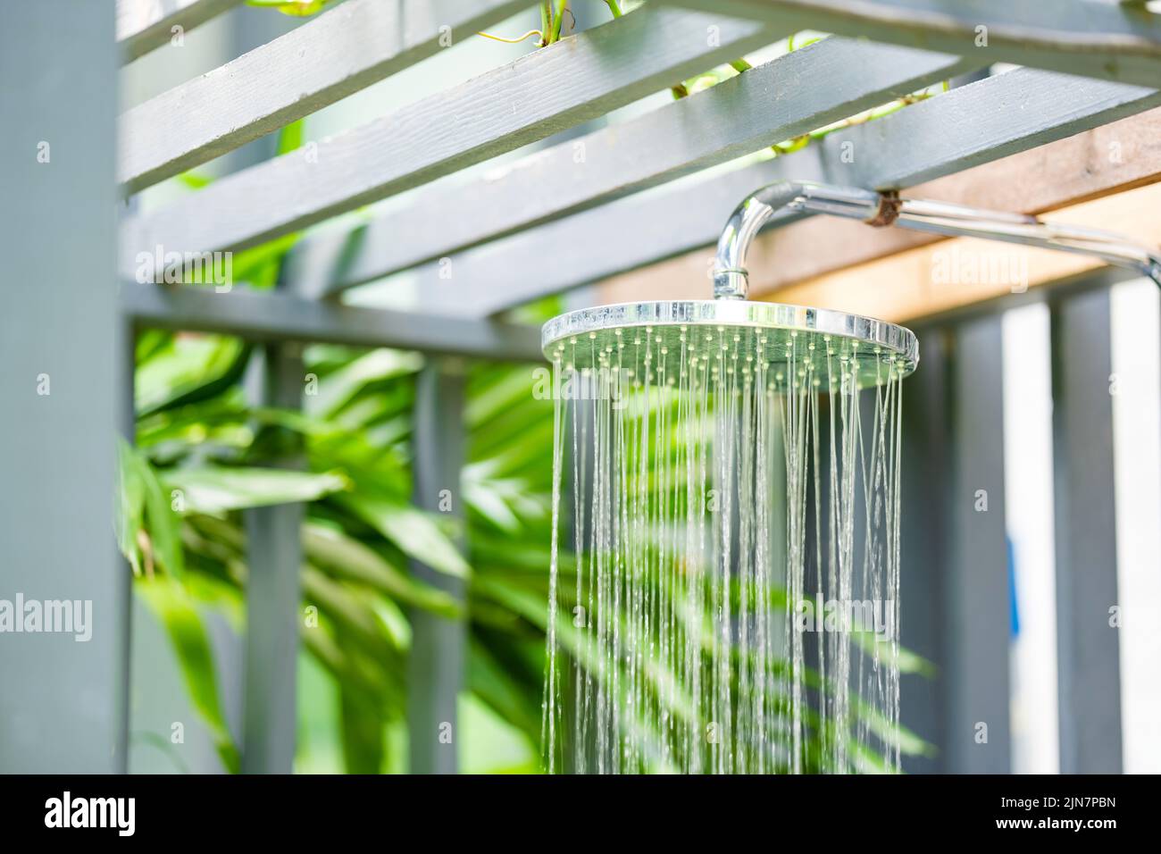 Outdoor pool bathroom open air style with rain shower beside swimming