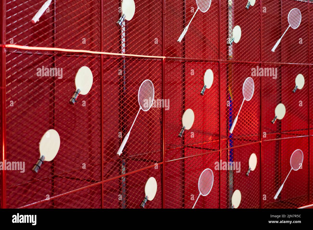 Table tennis and badminton rackets are hung on a red square grill steel ...