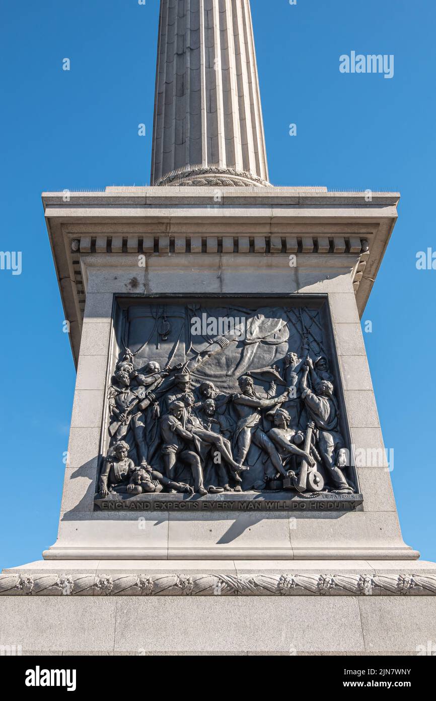 London, UK- July 4, 2022: Trafalgar Square. Closeup of black mural sculpture set in edestal of Nelson's Column depicts naval action scene saying Engla Stock Photo