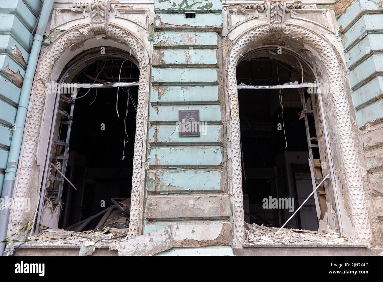 Damaged architectural monument of the city of Kharkiv. A commemorative plaque about the architectural value of the building is seen on the wall as well as broken windows due to Russian shelling in Kharkiv. Stock Photo