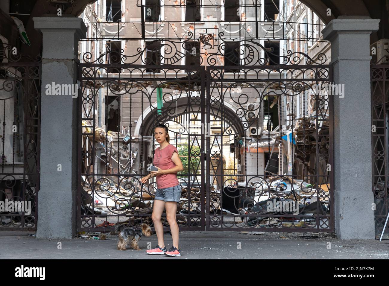 Kharkiv, Ukraine. 1st Aug, 2022. A young lady with a dog seen near the entrance to the courtyard of a damaged house. Destroyed building in historical downtown in Kharkiv, Ukraine - 1 Aug 2022 (Credit Image: © Mykhaylo Palinchak/SOPA Images via ZUMA Press Wire) Stock Photo