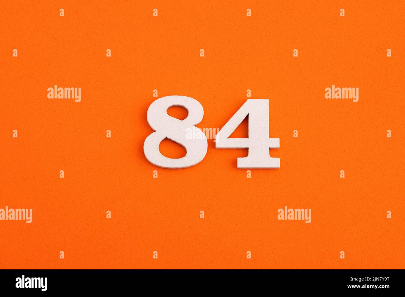 White wooden number 84 on eva rubber orange background Stock Photo - Alamy