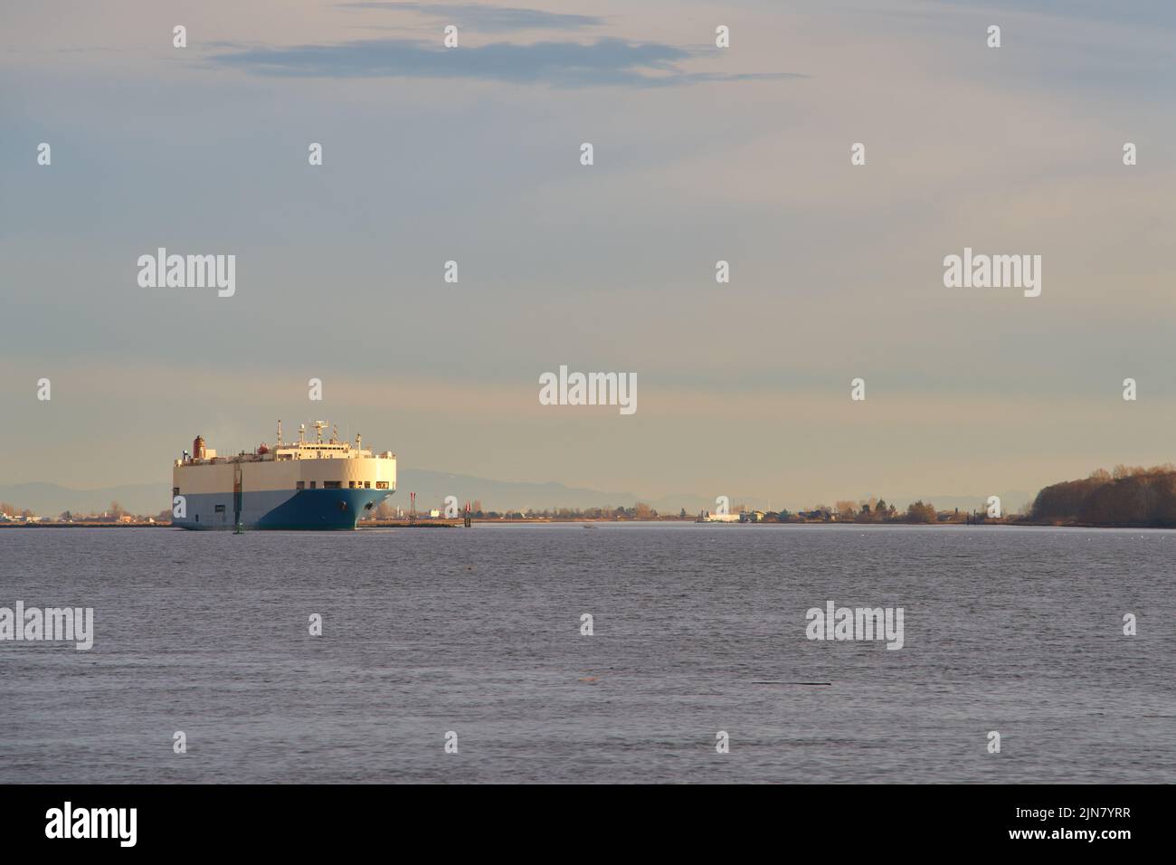 Morning Car Freighter Underway Fraser River. Grey sky behind a car carrier freighter as it moves down river. British Columbia, Canada. Stock Photo