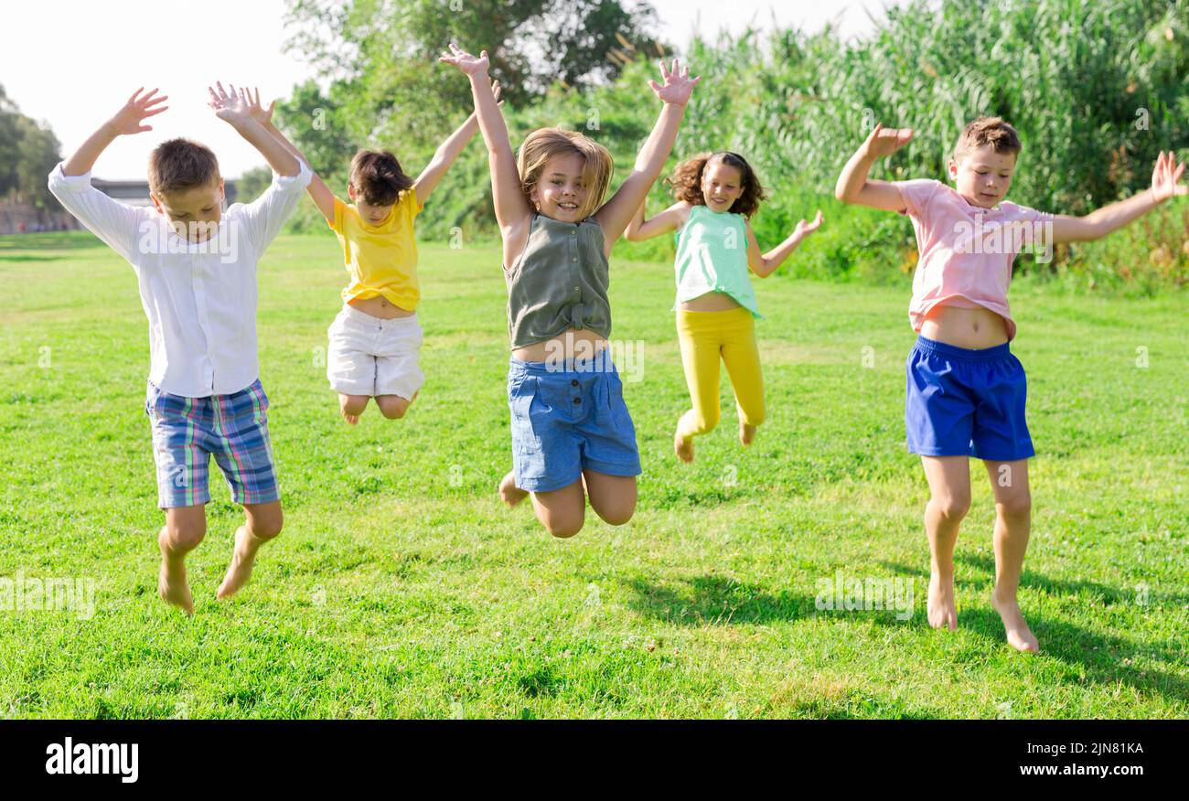 Group of five happy children jumping outdoors., Group of fi…