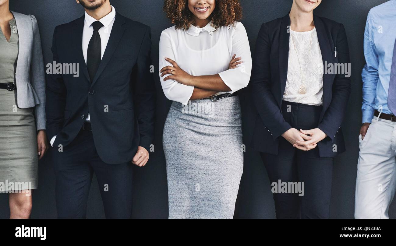 Group of corporate business people standing against a wall, to voice their opinion. Team of many work colleagues in line wearing formal suit for Stock Photo