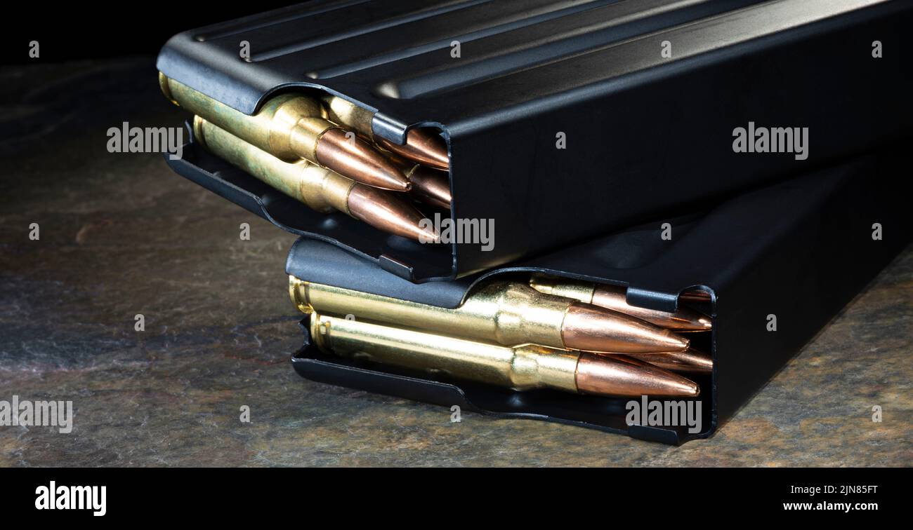 Metal magazines fully loaded with ammunition on a dark stone surface Stock Photo