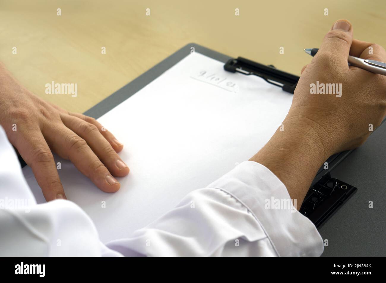Closeup doctor hand holding a pen, writing on the clipboard. Healthcare