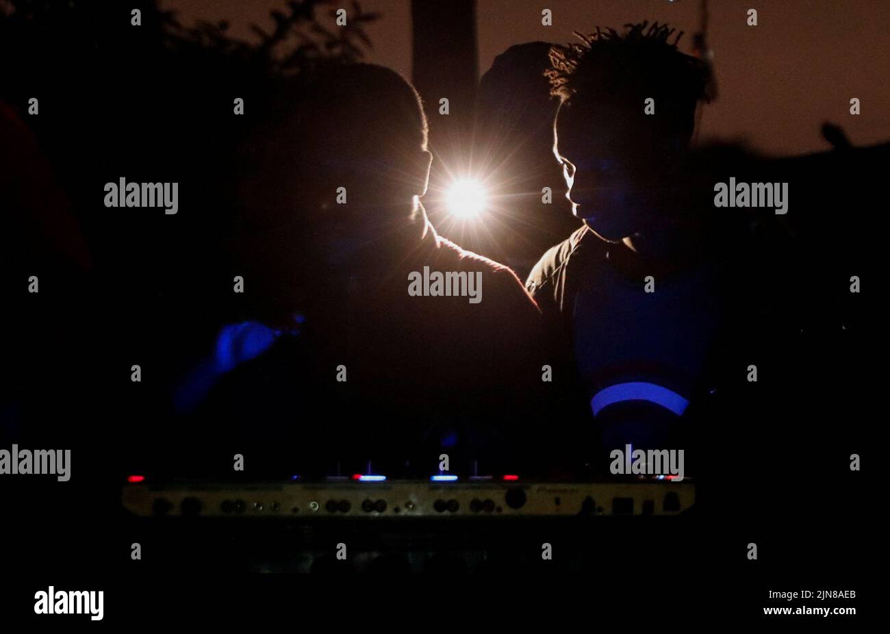 Disc jockeys play music as people use a projector to follow the counting of the casted votes in the general election conducted by the Independent Electoral and Boundaries Commission (IEBC), in Kibera slums of Nairobi, Kenya August 10, 2022. REUTERS/Thomas Mukoya Stock Photo