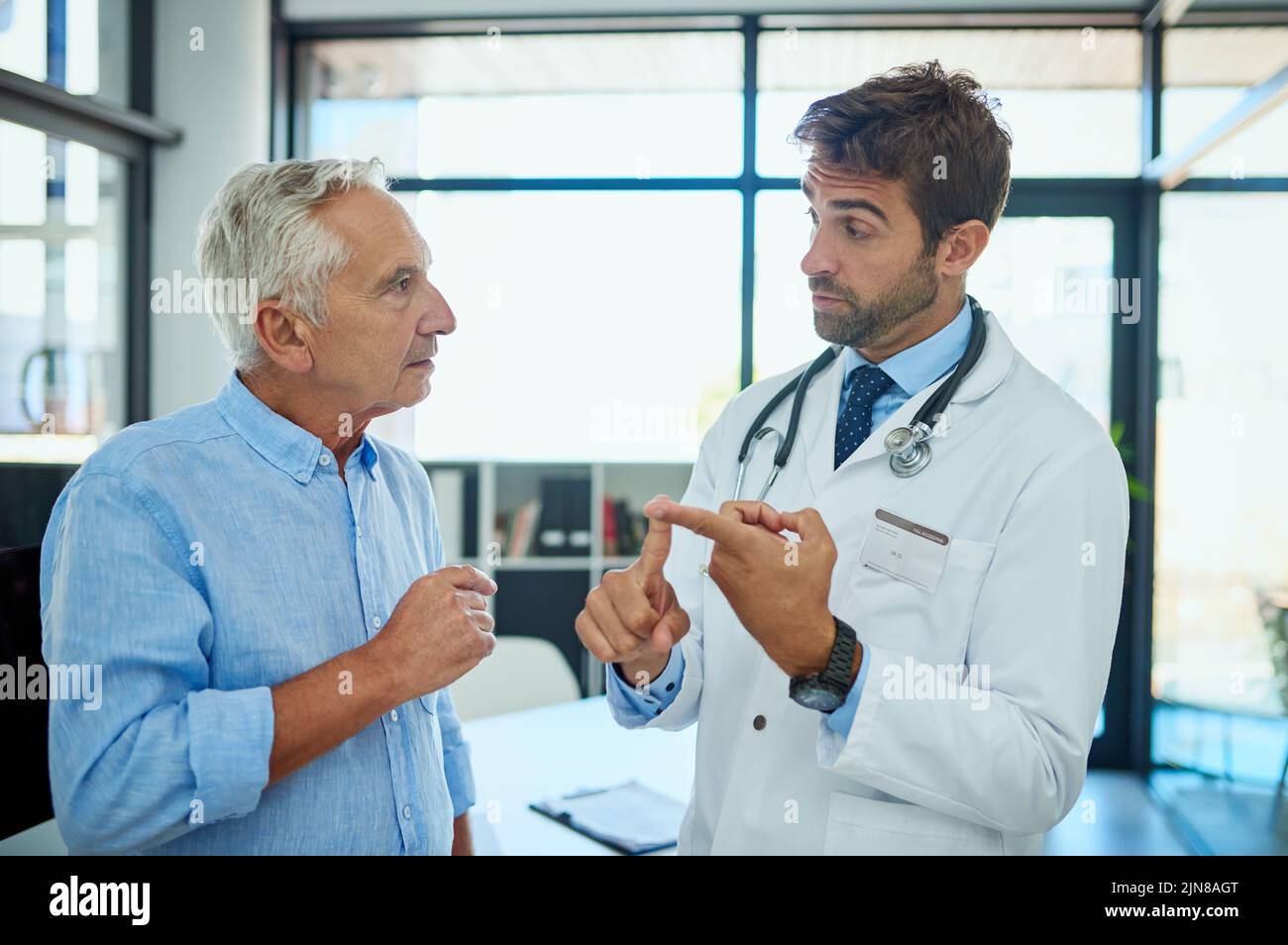Guiding him through the steps of recovery. a doctor consulting a male senior patient in his office. Stock Photo