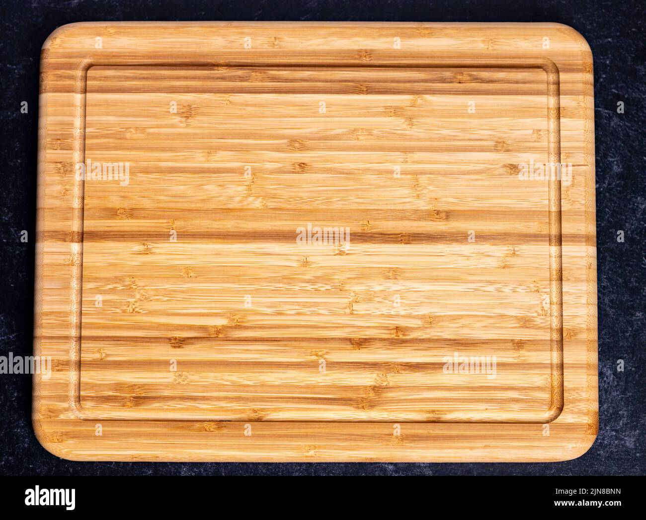 The top view of a rectangular wooden chopping board on the dark-colored ...