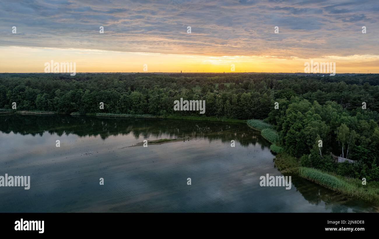 Aerial view, shot by a drone of a sunset at coast of the lake. Nature landscape. Nature in northern Europe. reflection, blue sky and yellow sunlight. landscape during sunset. High quality photo Stock Photo