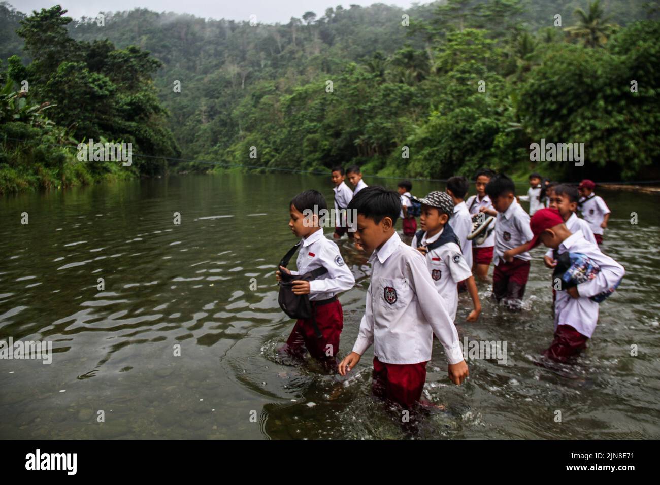 Sukaluyu Village, West Java, Indonesia. 10th Aug, 2022. Students crossed the Ciujung river as they headed to school in Sukaluyu village, South Cianjur. Hundreds students in Sukaluyu Village, Cikadu District, Cianjur, West Java, Indonesia were forced to cross a Ciujung river on their way to school, because the suspension bridge was lost due to flash floods several years ago and has not been repaired until now. If it rains heavily, the children are forced to skip school. Credit: ZUMA Press, Inc./Alamy Live News Stock Photo