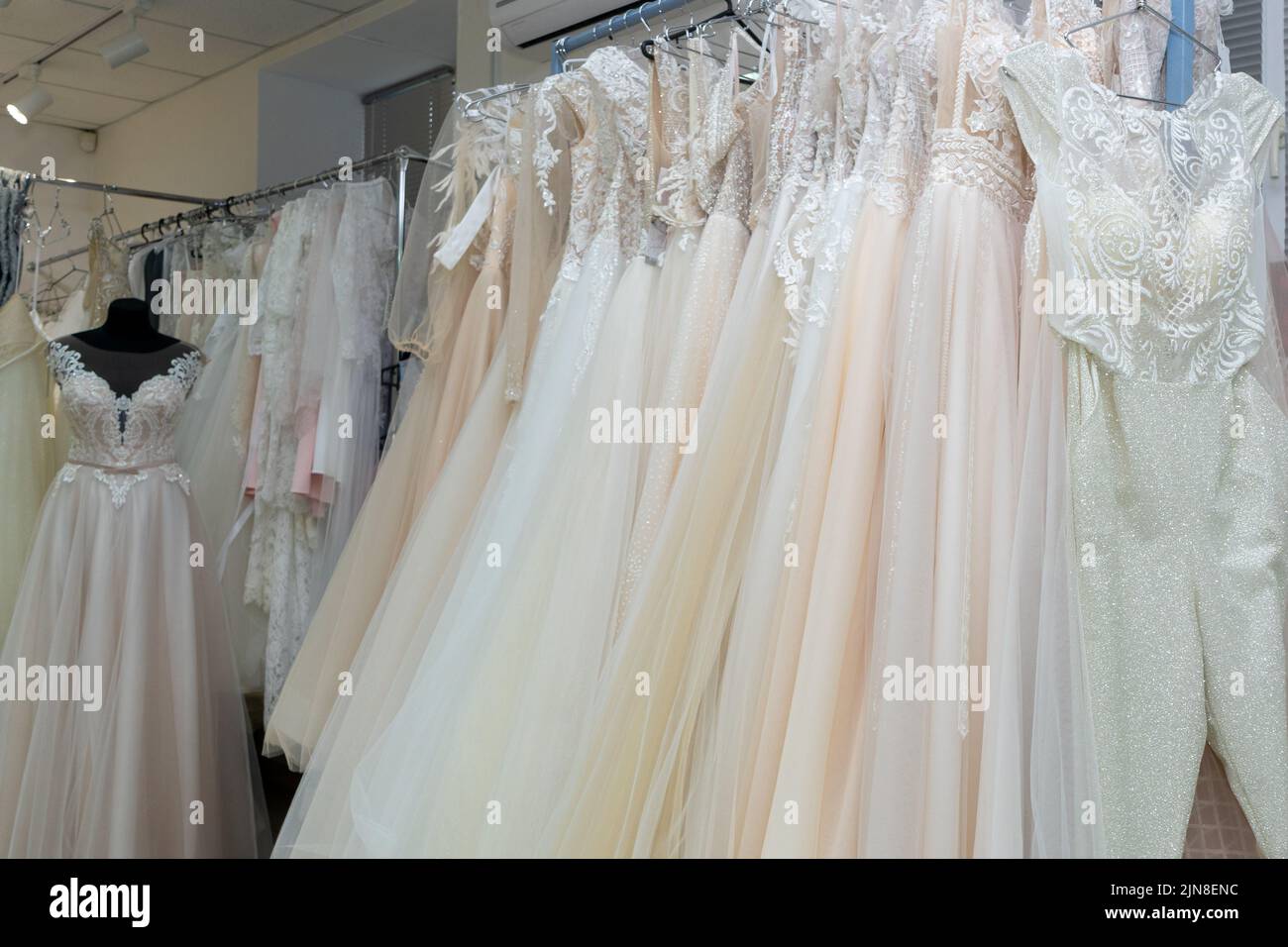 White and cream wedding dresses on a hanger in a bridal boutique. Close up. Stock Photo