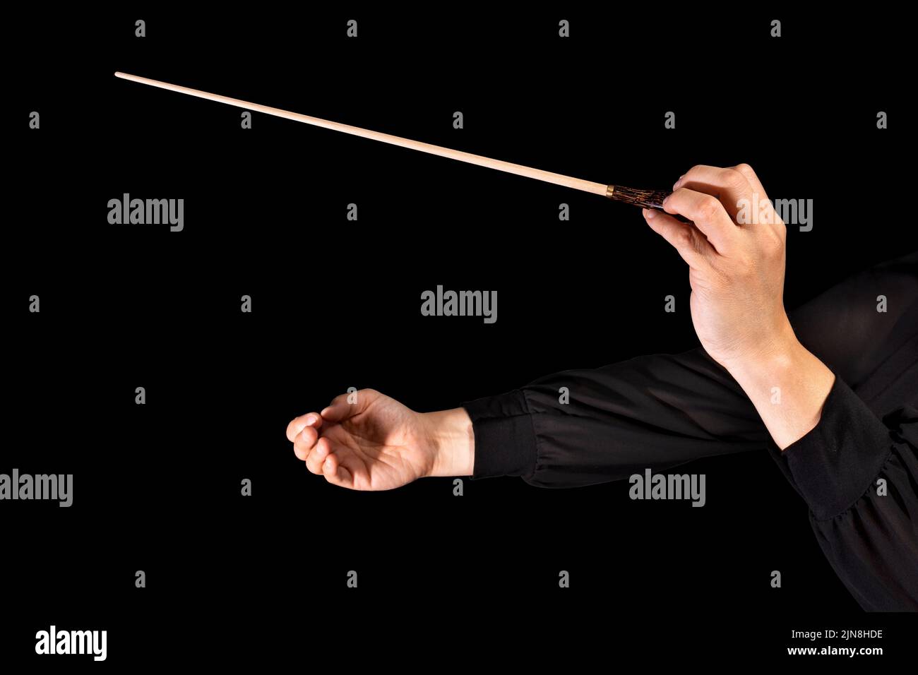 Female conductor conducting a symphony with her baton on a black background Stock Photo Alamy