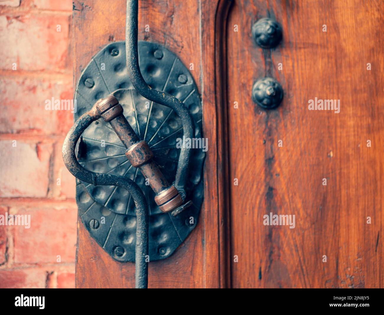 Old metal doorknob on the old wooden door, selective focus. Vintage forged padlock and door handle, close up Stock Photo