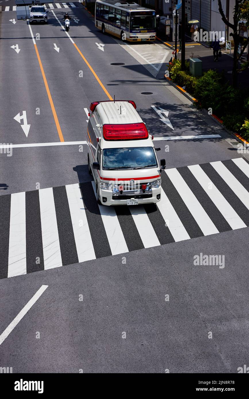 Japanese ambulance driving across a pedestrian crossing; Tokyo, Japan Stock Photo