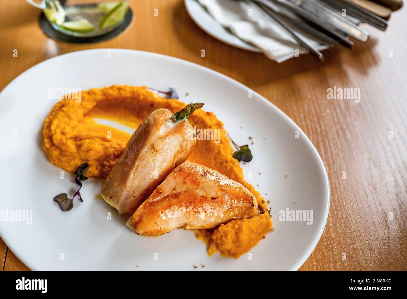 Roasted turkey meat with mashed pumpkin, cutlery and glass on table, closeup. Stock Photo