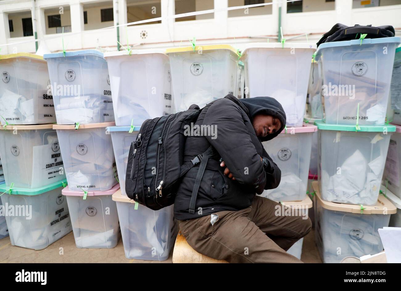 A polling staff sleeps next to the sealed ballot boxes containing electoral materials at an Independent Electoral and Boundaries Commission (IEBC) tallying centre after the general election in Nairobi, Kenya August 10, 2022. REUTERS/Thomas Mukoya Stock Photo
