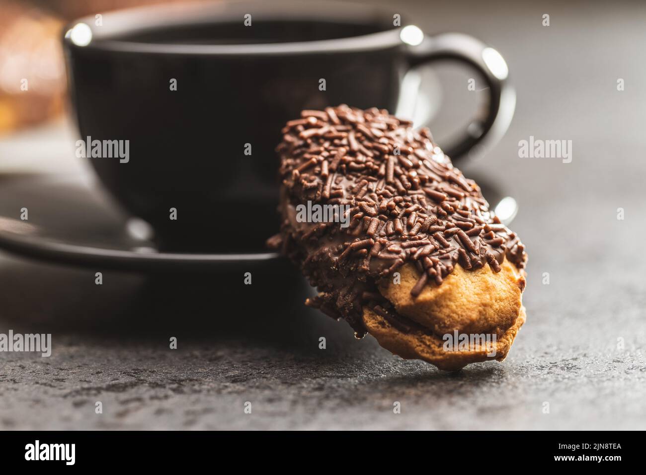 Petit fours with chocolate sprinkles. Mini chocolate dessert and a coffee cup. Stock Photo