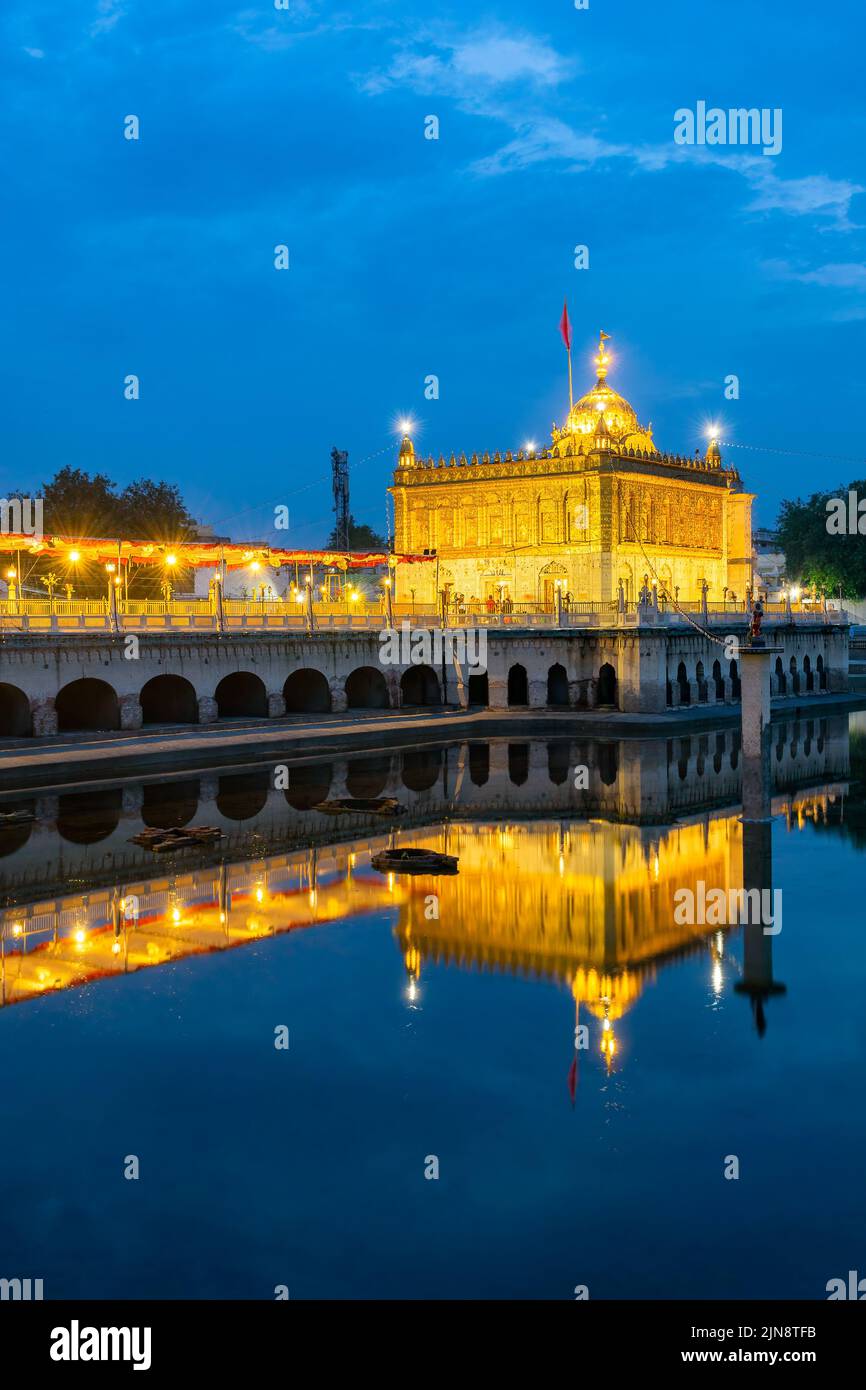 The illuminated Shri Durgiana Temple reflected in the lake in Amritsar, Punjab, India Stock Photo