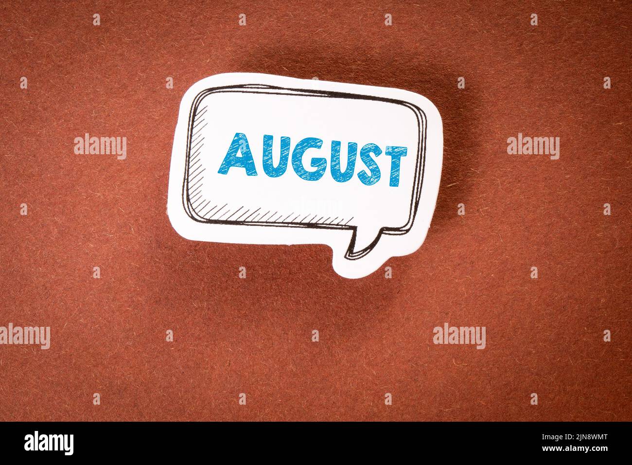 August. Planning and vacation concept. Speech bubble with text on brown background. Stock Photo