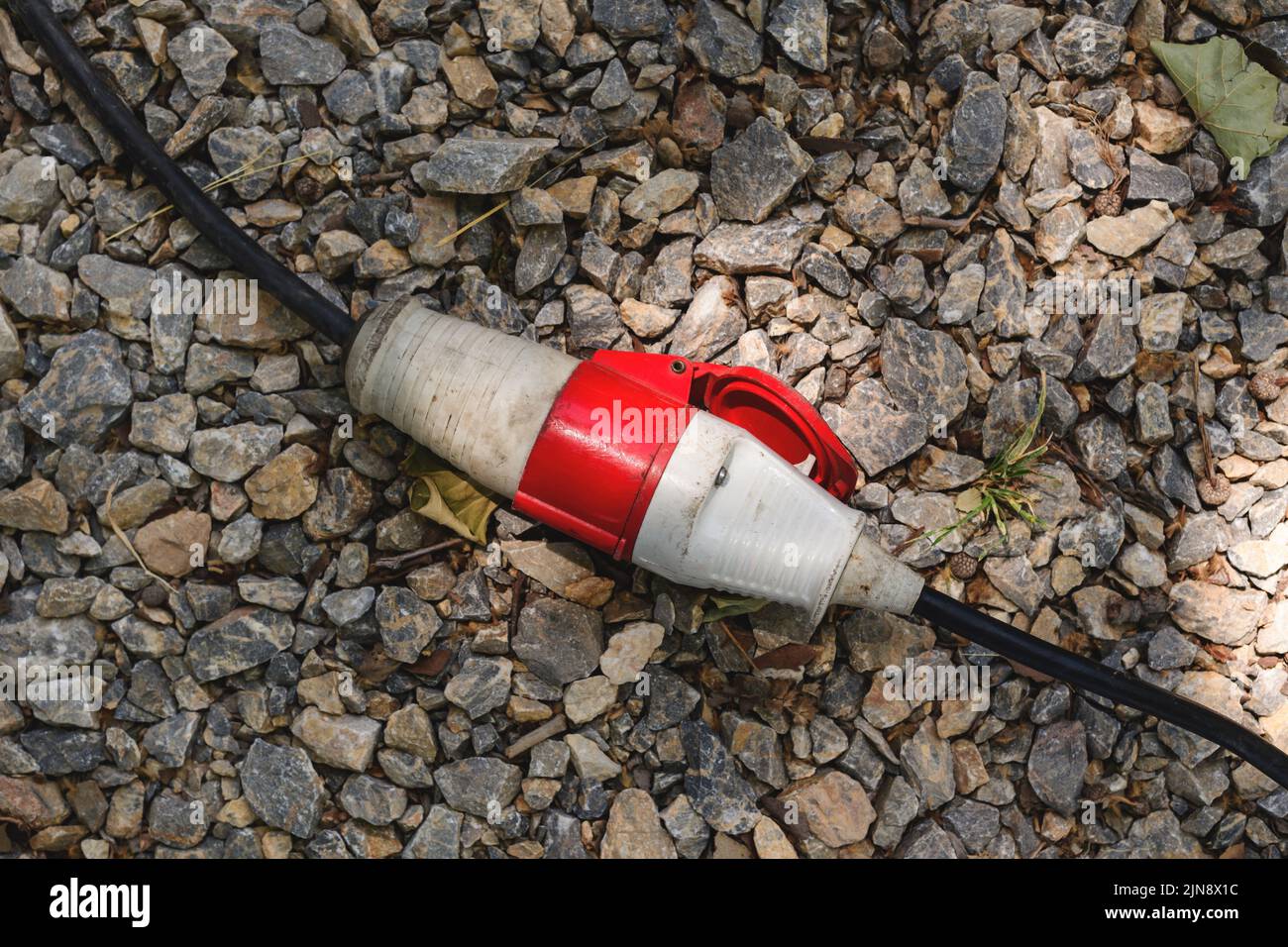Electrical cord connector on the ground outdoor, top down Stock Photo