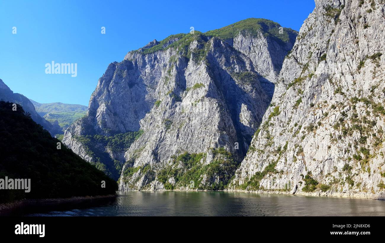 Lake Koman is a reservoir on the Drin River in northern Albania, surrounded by dense forested hills, vertical slopes, deep gorges and a narrow valley Stock Photo