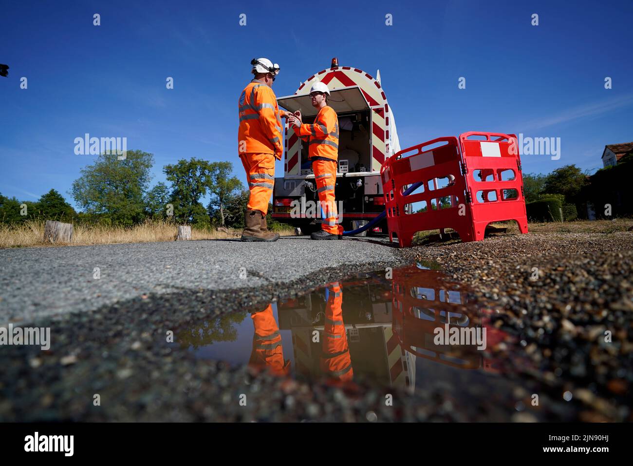 Workers from Thames Water delivering a temporary water supply from a tanker to the village of Northend in Oxfordshire, where the water company is pumping water into the supply network following a technical issue at Stokenchurch Reservoir in Oxfordshire. TPicture date: Wednesday August 10, 2022. Stock Photo