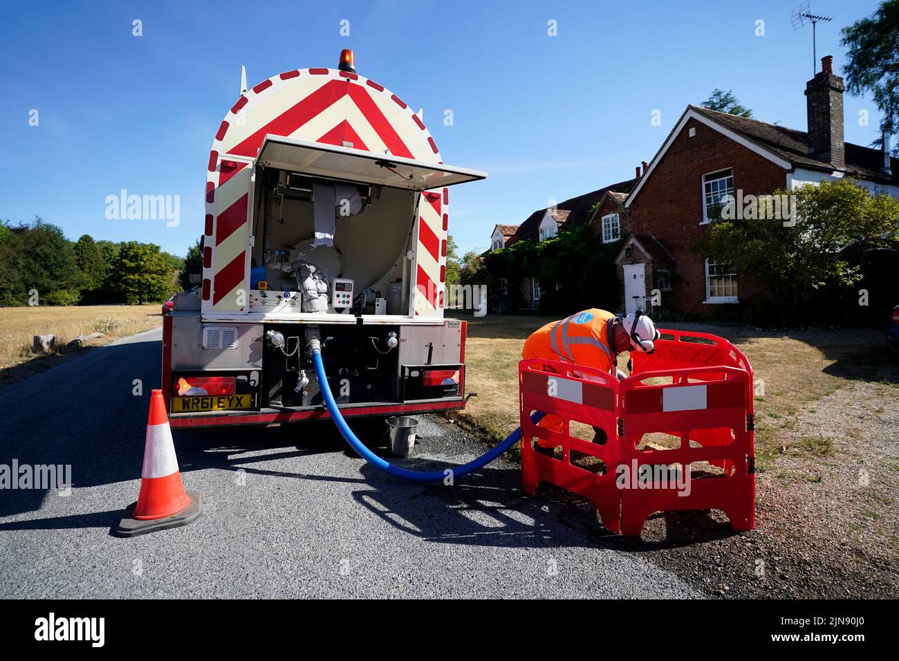 A worker from Thames Water delivering a temporary water supply from a tanker to the village of Northend in Oxfordshire, where the water company is pumping water into the supply network following a technical issue at Stokenchurch Reservoir in Oxfordshire. TPicture date: Wednesday August 10, 2022. Stock Photo