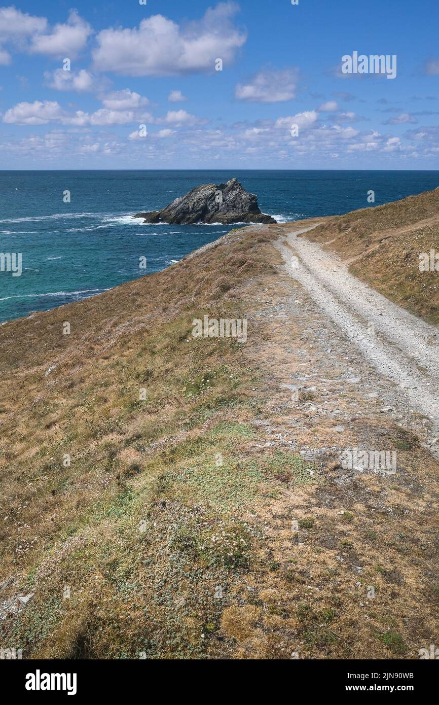 A rough footpath leading to a view of the rocky island The Goose off coast of Pentire Point East in Newquay in Cornwall in the UK. Stock Photo