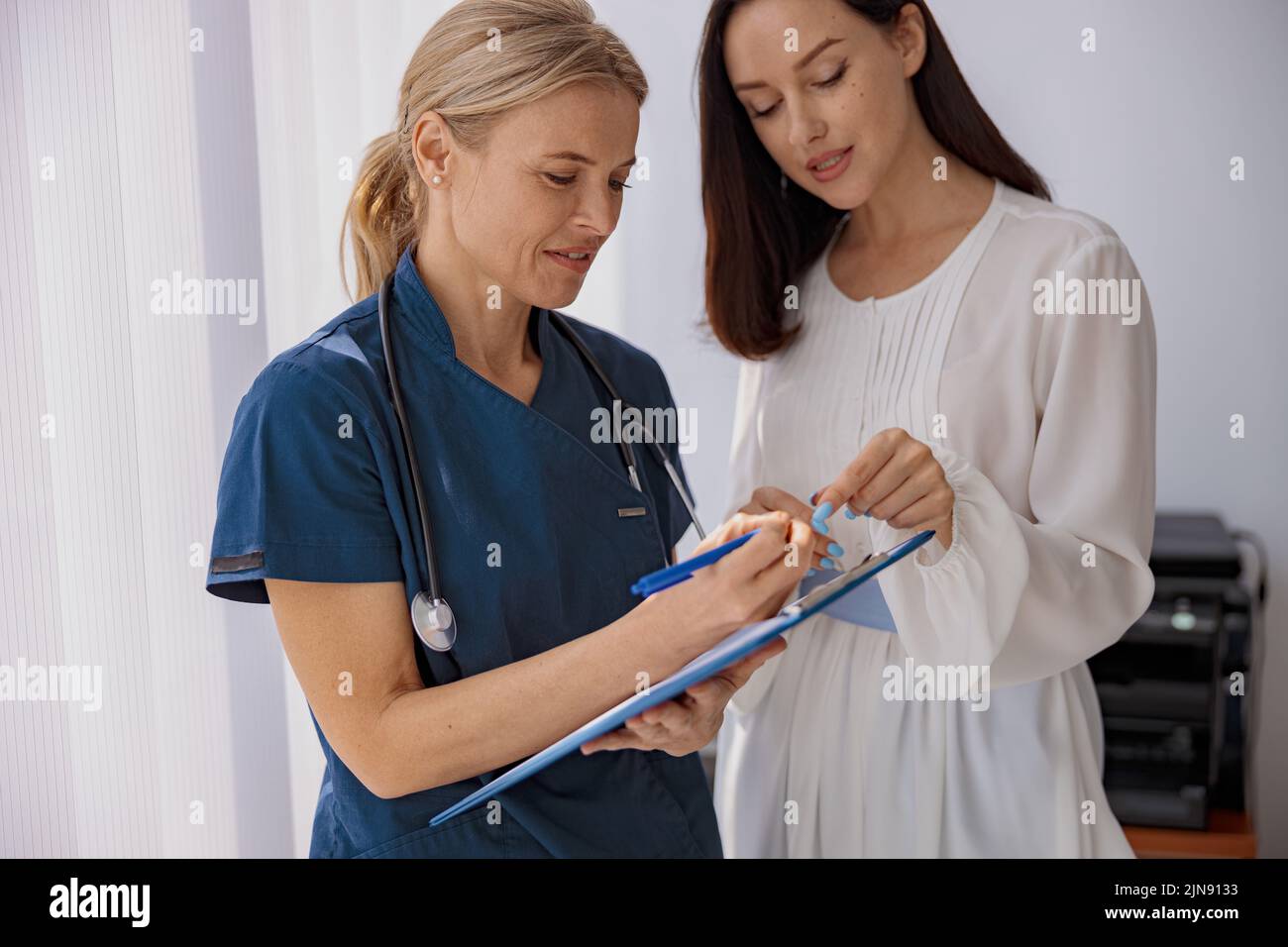 Doctor fills out the medical report form on medical care of patients during appointment Stock Photo