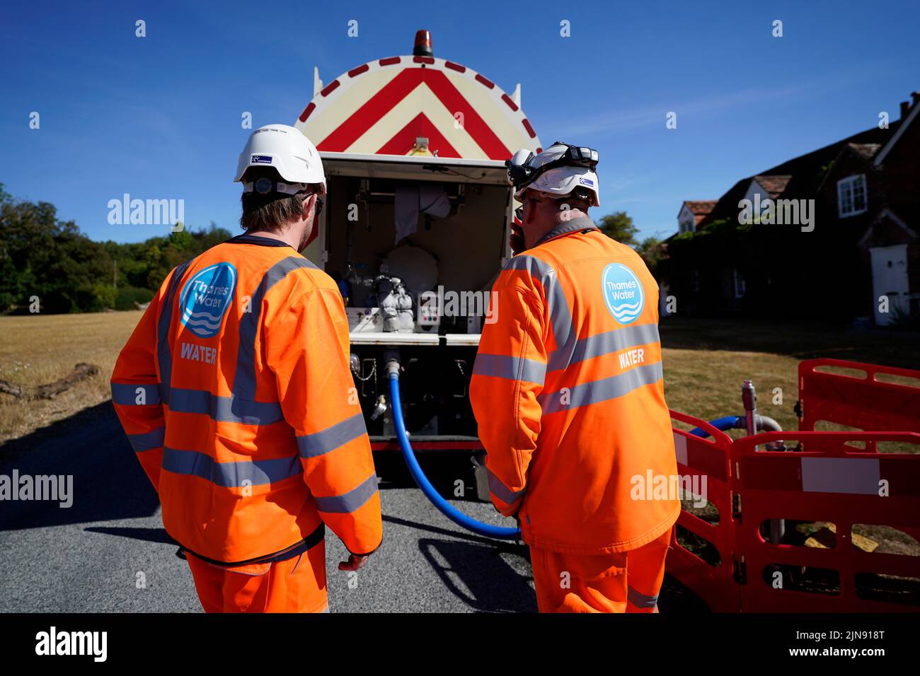 A worker from Thames Water delivering a temporary water supply from a tanker to the village of Northend in Oxfordshire, where the water company is pumping water into the supply network following a technical issue at Stokenchurch Reservoir. TPicture date: Wednesday August 10, 2022. Stock Photo