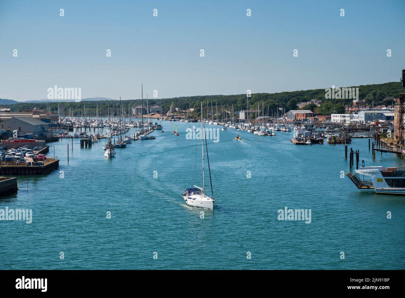 A sail boat makes its way down the River Medina in Cowes on the Isle of Wight. Stock Photo