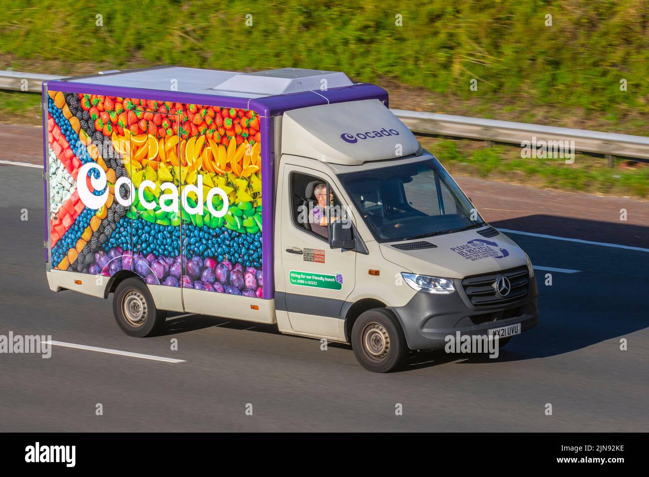 Ocado new rainbow Fruit Van livery & Morrisons supermarket grocery delivery service food store vehicles; online delivery fleet delivering, deliveries, groceries & household essentials; travelling on the M6 motorway, UK Stock Photo