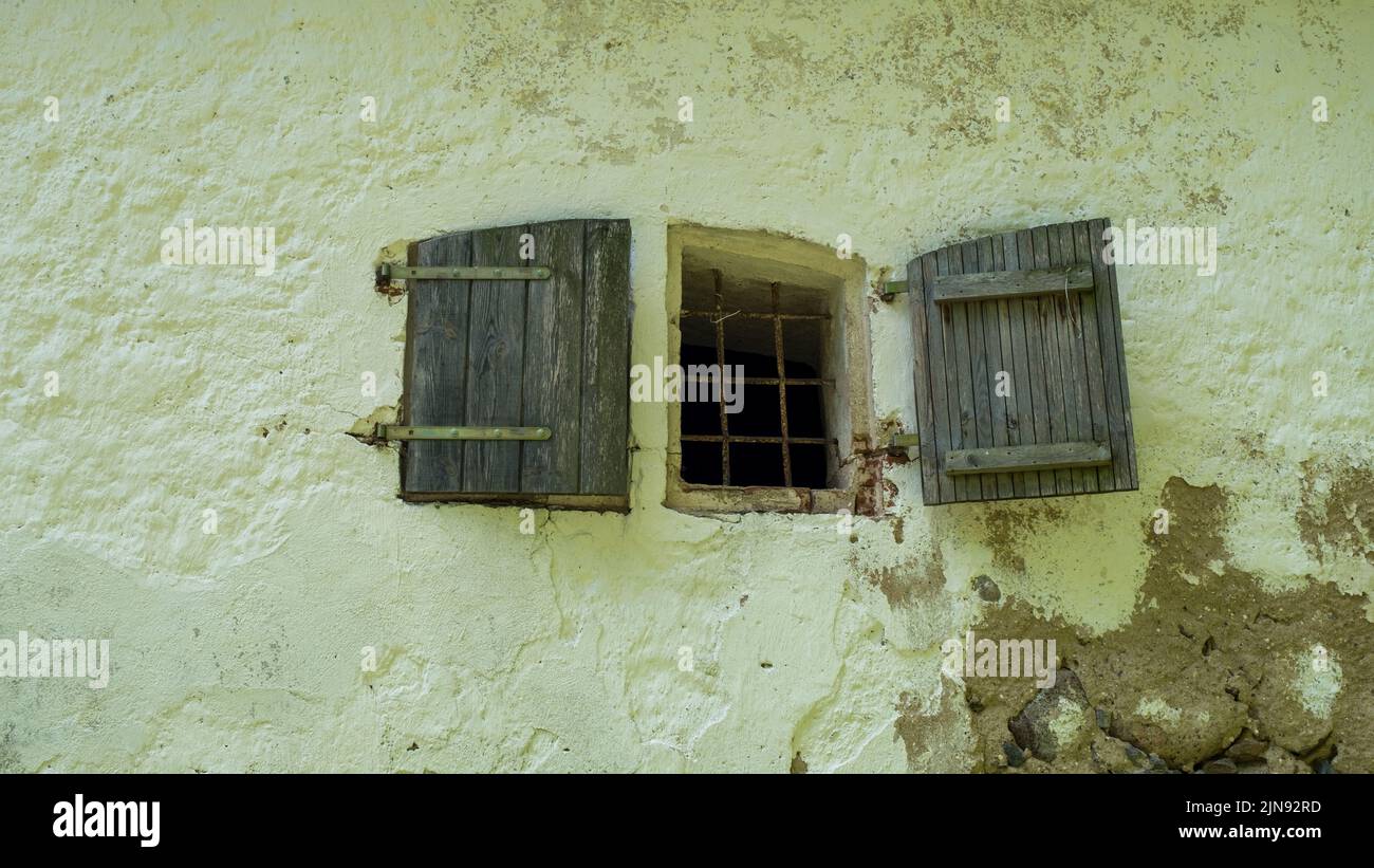 Concrete brick wall and small windows of an abandoned old building exterior. Stock Photo