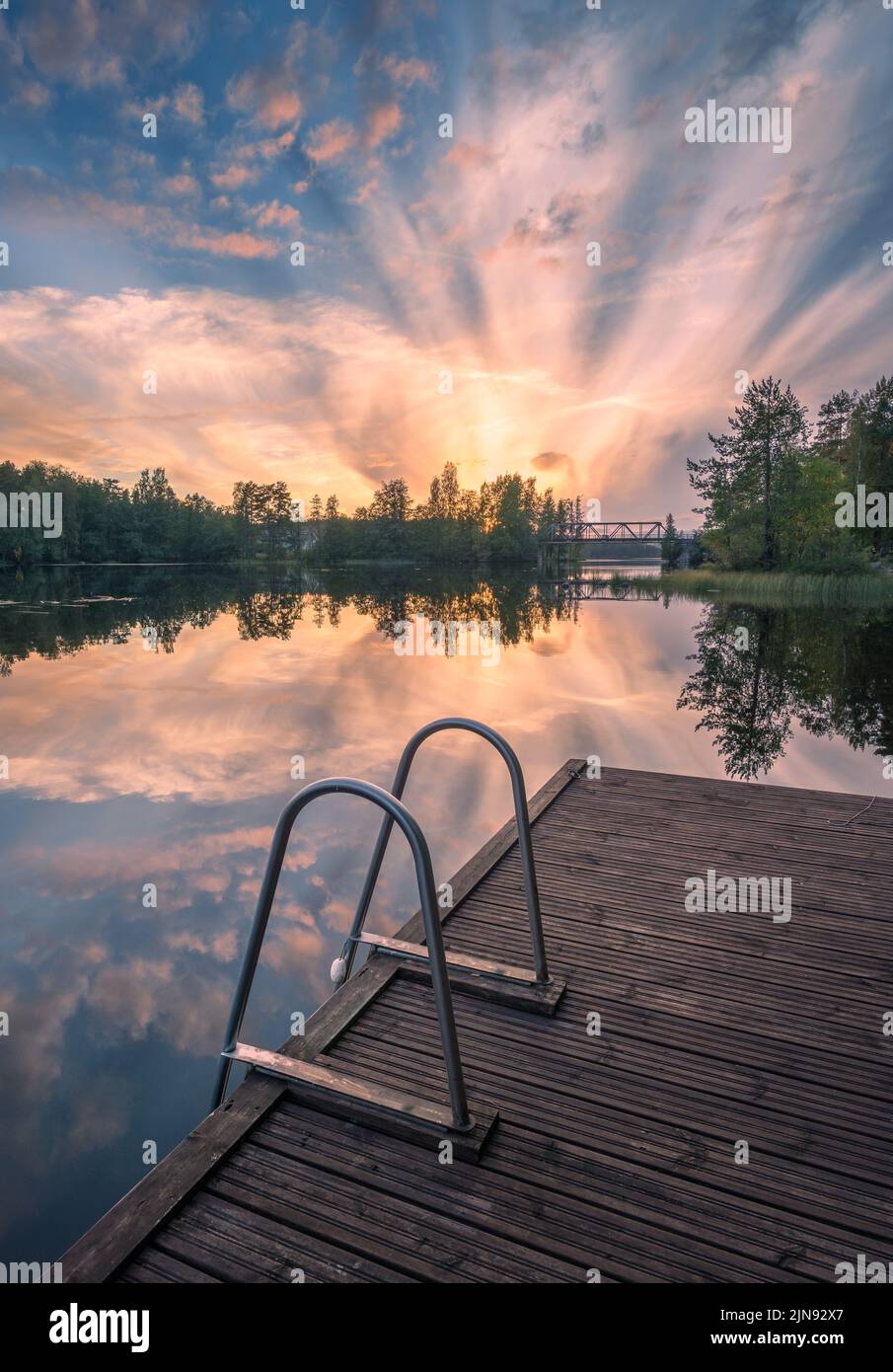 Beautiful sunset in tranquil lake at summer evening in Finland with pier Stock Photo