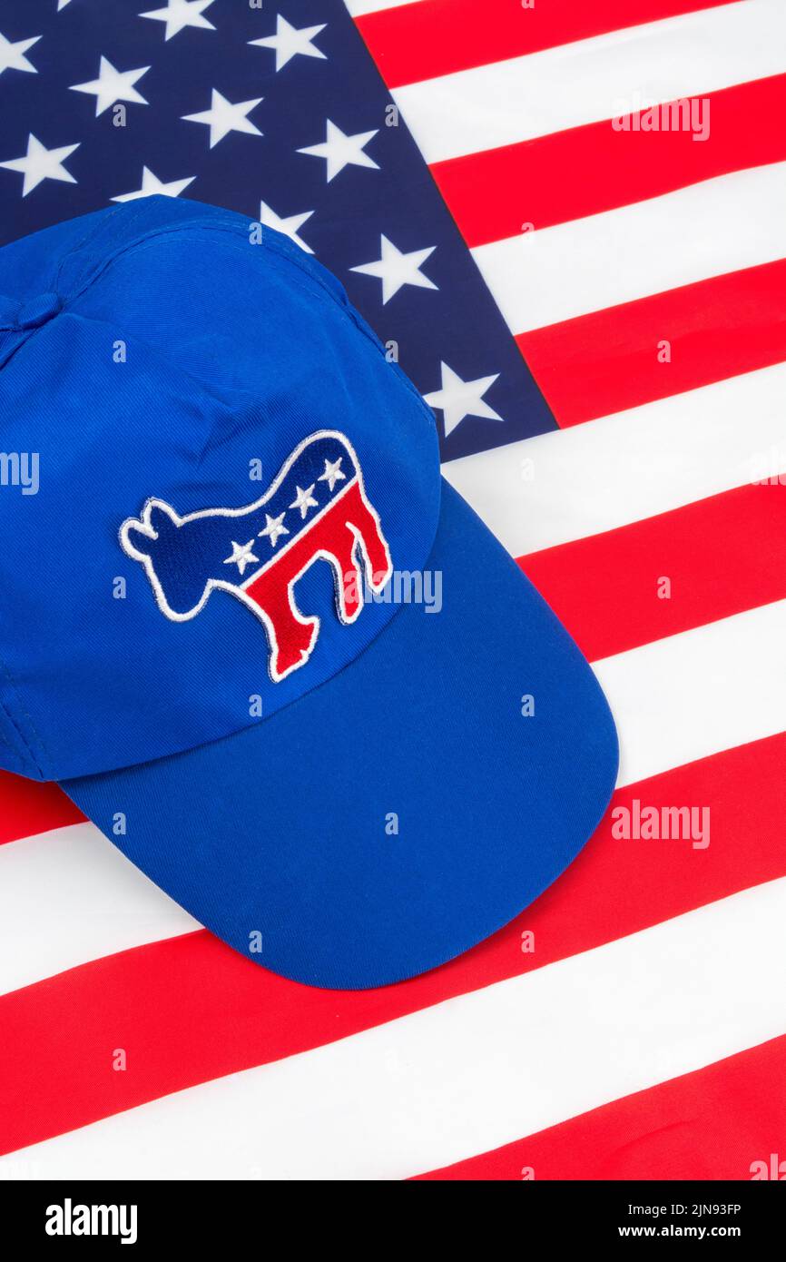Blue DNC cap with Dem donkey badge & US Stars and Stripes flag. For 2024 US Presidential election & Republican Red Wave wipe-out of Democrats. Stock Photo
