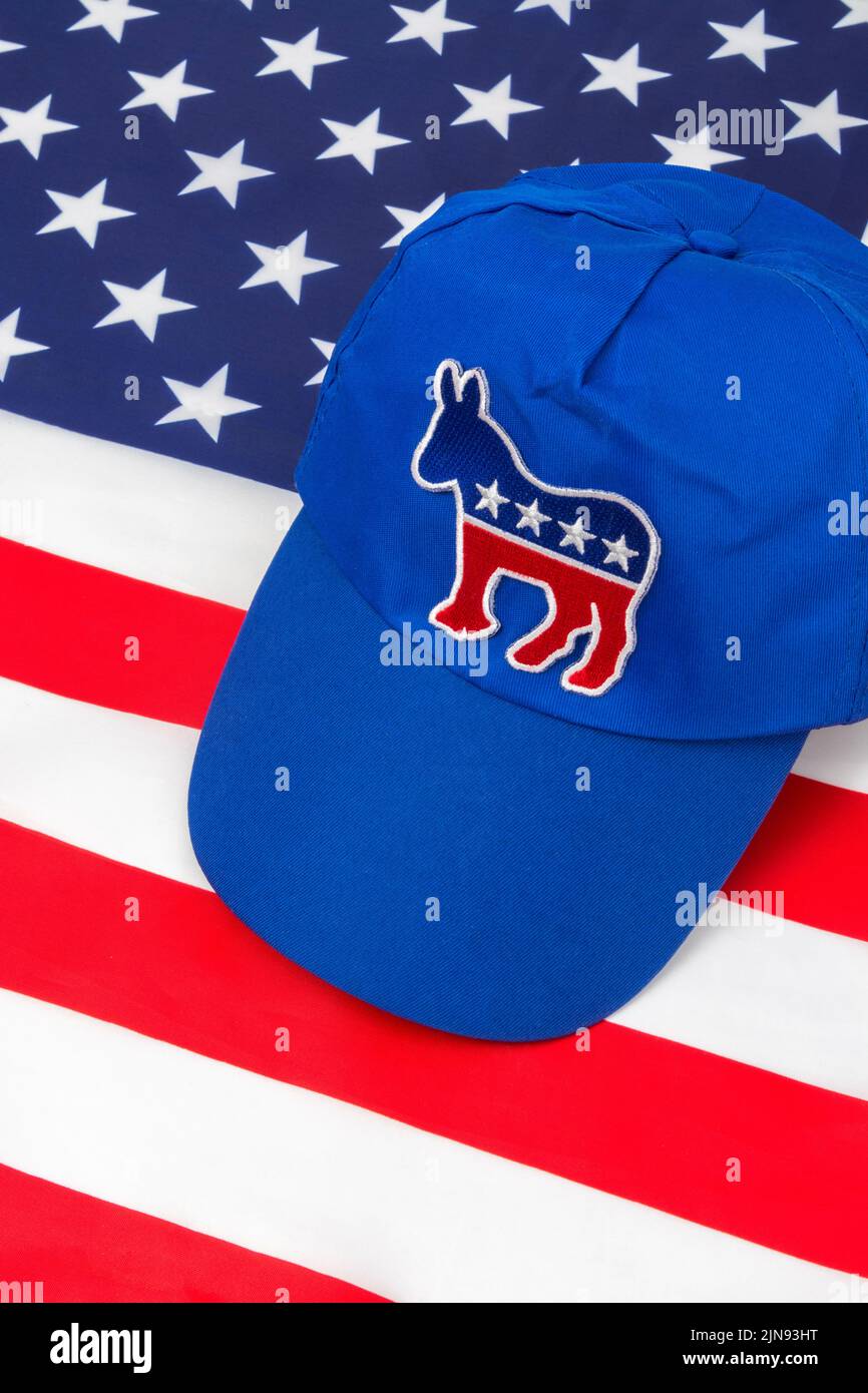 Blue DNC cap with Dem donkey badge & US Stars and Stripes flag. For 2024 US Presidential election & Republican Red Wave wipe-out of Democrats. Stock Photo