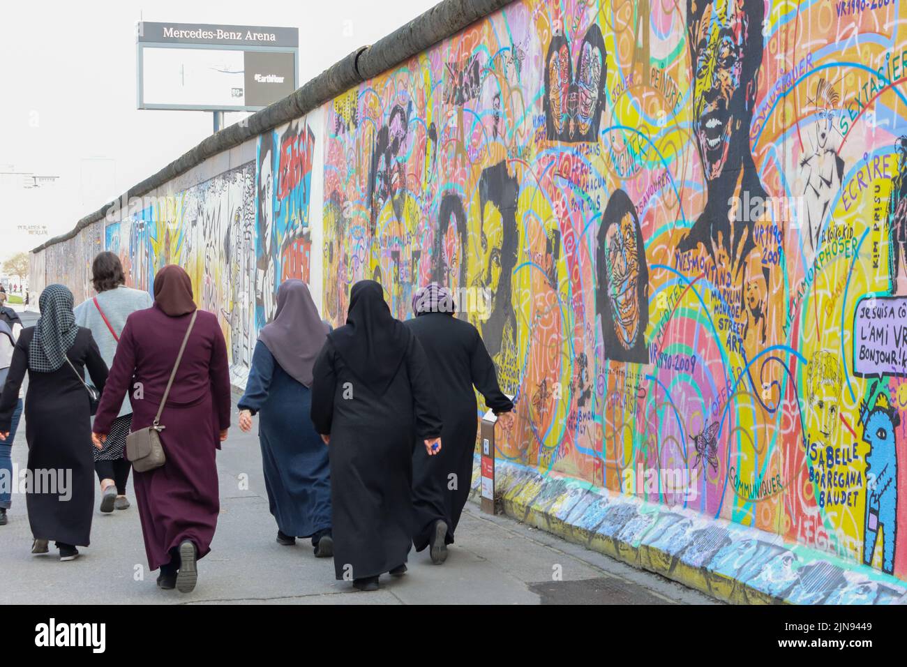 A group of Muslim women walk along the Berlin Wall Stock Photo