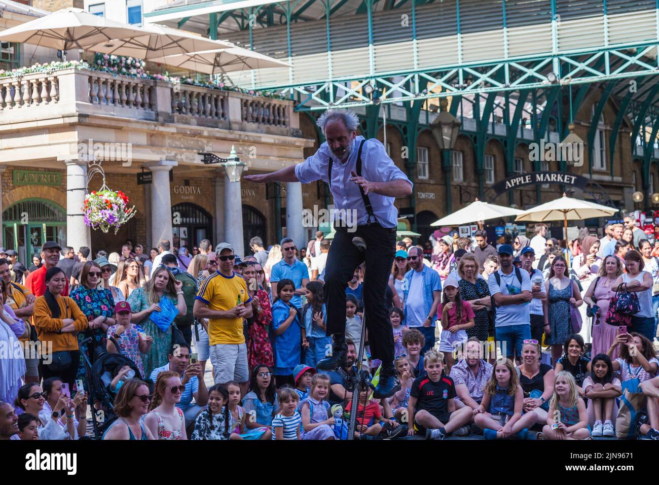 A male juggler entertaining crowds on a unicycle in Covent Garden,London,England,UK Stock Photo