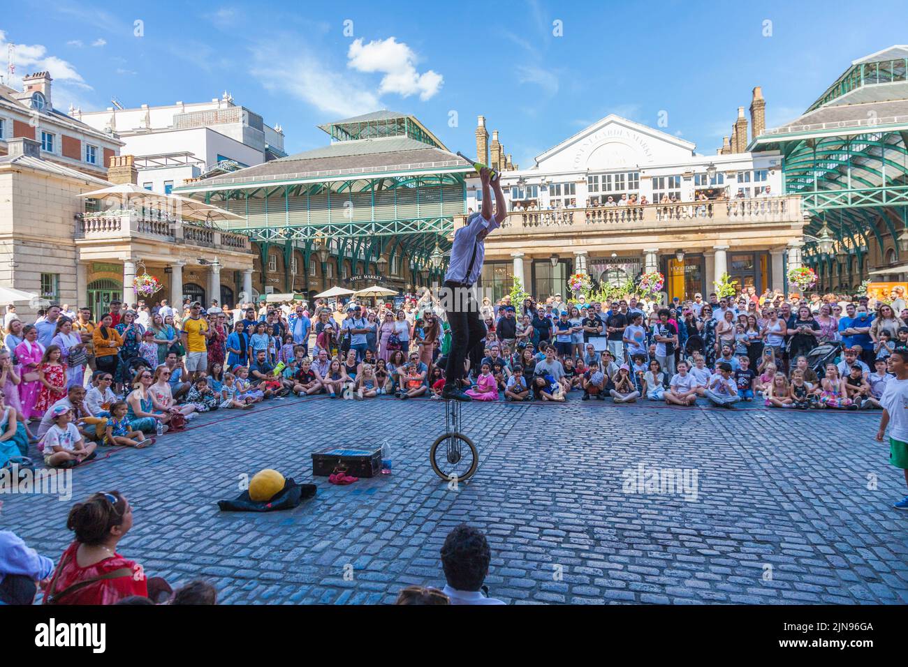 A male juggler entertaining crowds on a unicycle in Covent Garden,London,England,UK Stock Photo