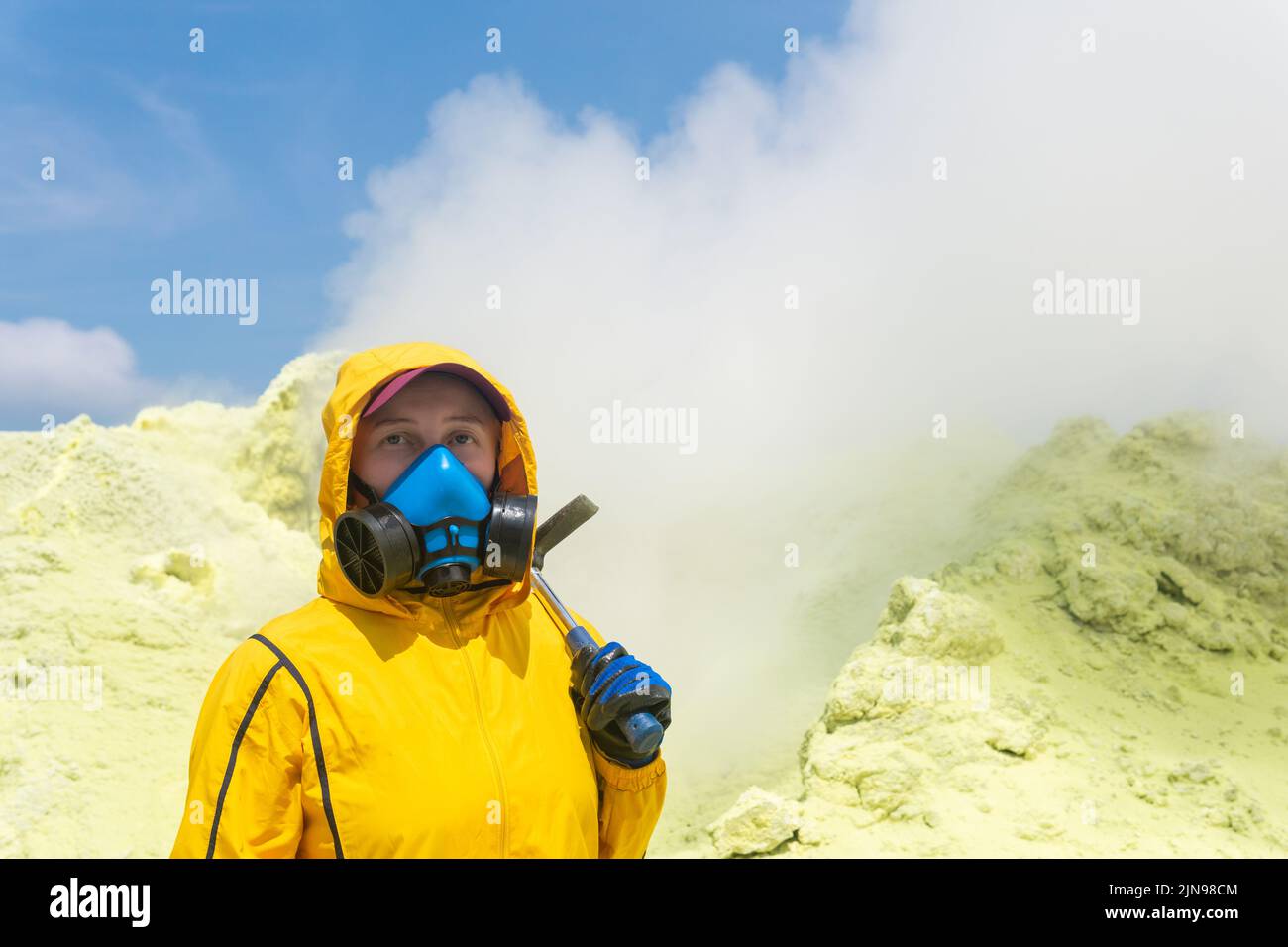 female volcanologist with a geological hammer and in a respirator