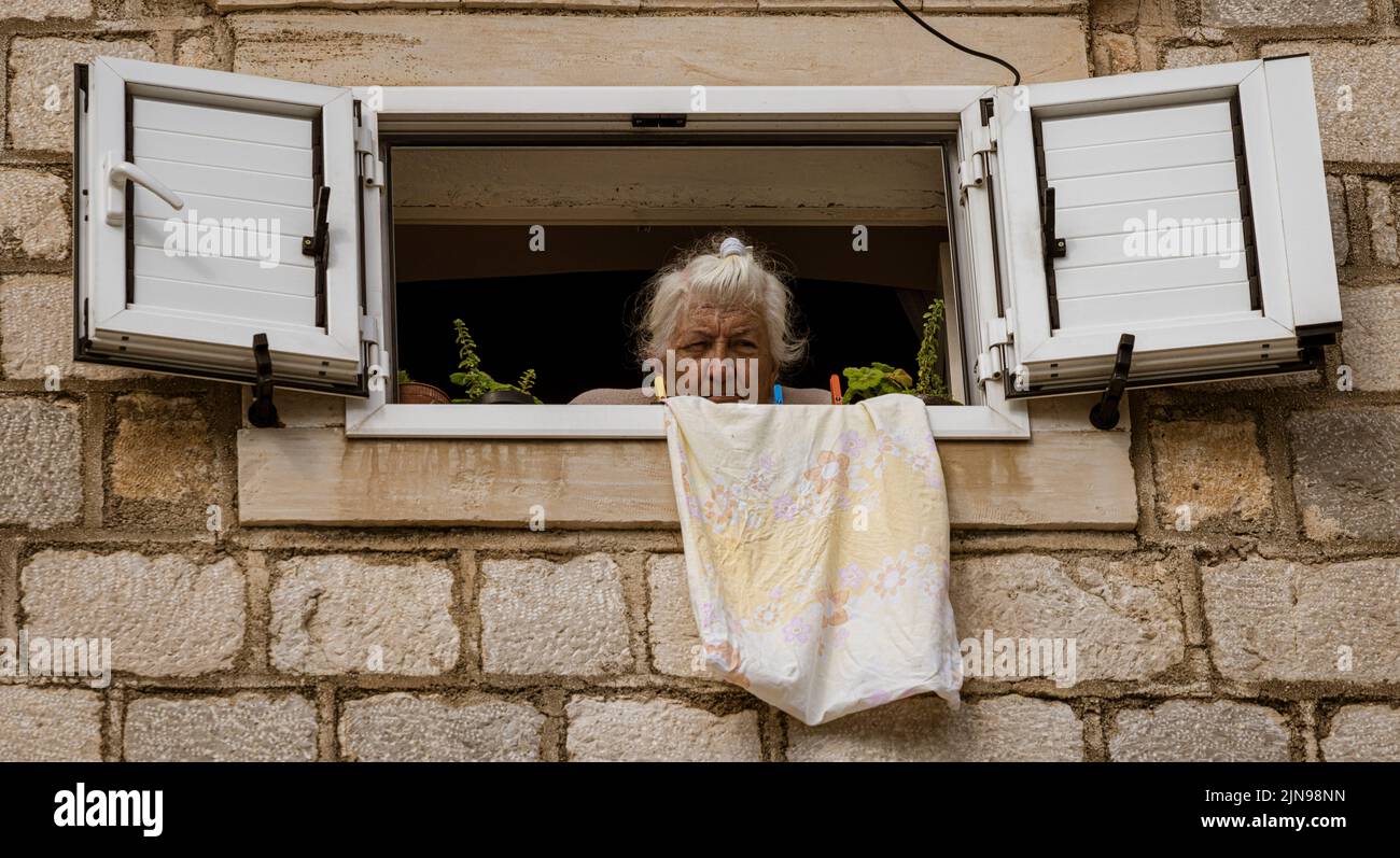 Montenegro - May 7, 2022 - Old woman looks out her upper floor window ...