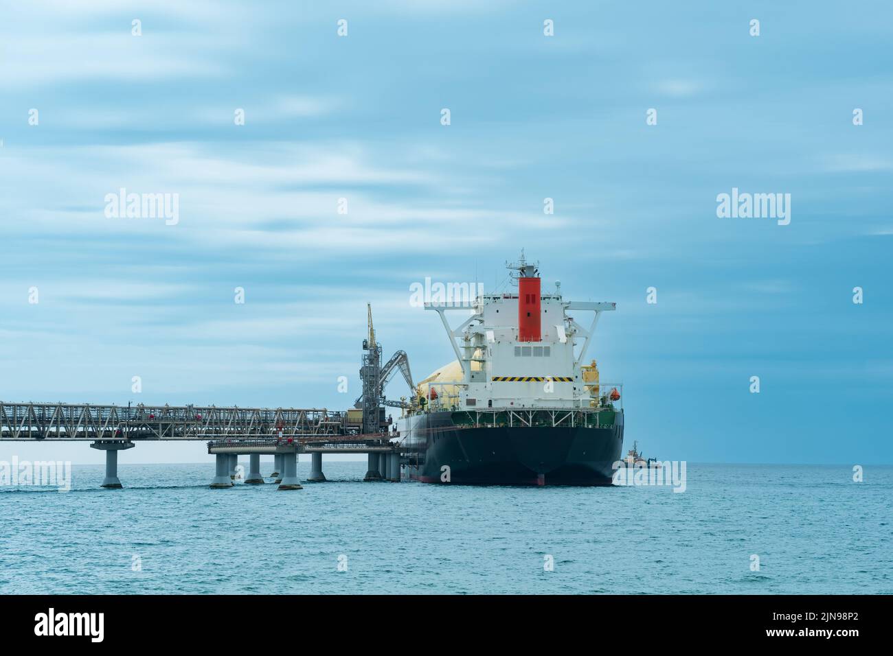 liquefied natural gas carrier tanker during loading at an LNG offshore terminal, in the distance